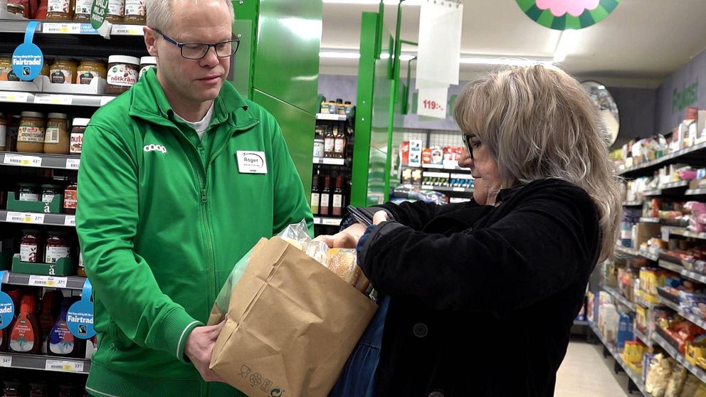 En handlare i en matbutik ger Isabel Hermansson en papperskasse med varor som har kort bäst före-datum.