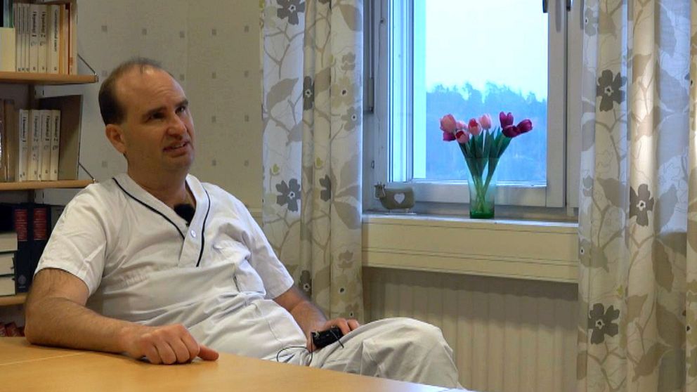 Bild på en man i vita läkarkläder som sitter lutad mot ett bord i ett rum vid ett fönster med tulpaner. Mannen heter Marcus Lind och är professor i diabetolog vid Göteborgs universitet. Han är med i en studie om diabetes.