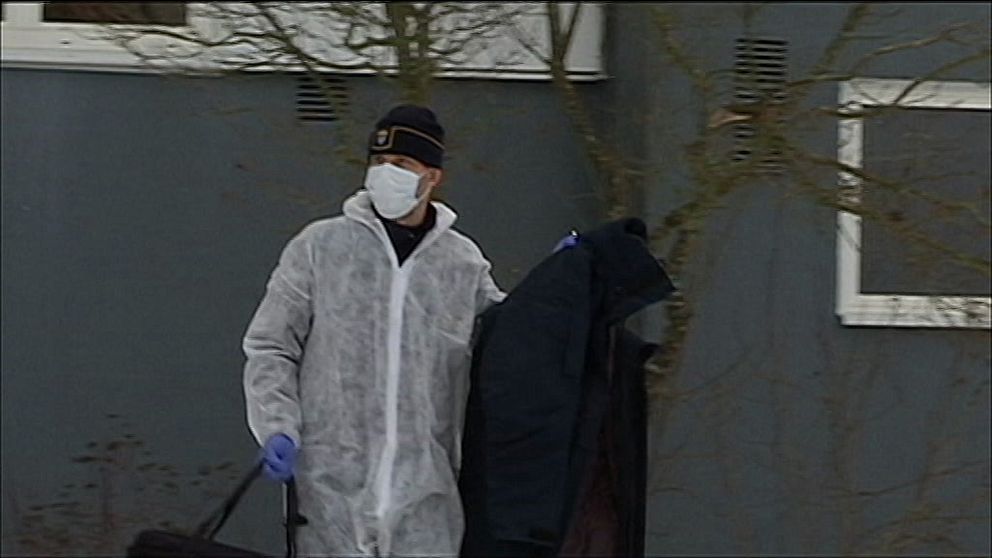 En kriminaltekniker bär ut ett klädesplagg från platsen där mordet ska ha ägt rum.