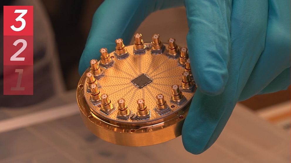 En del av en kvantdator hålls upp av en person i gummihandskar.