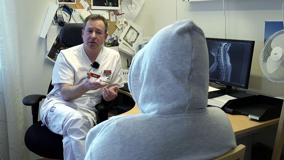 Läkare diskuterar med patient i huva framför en datorskärm som visar röntgenbilder.