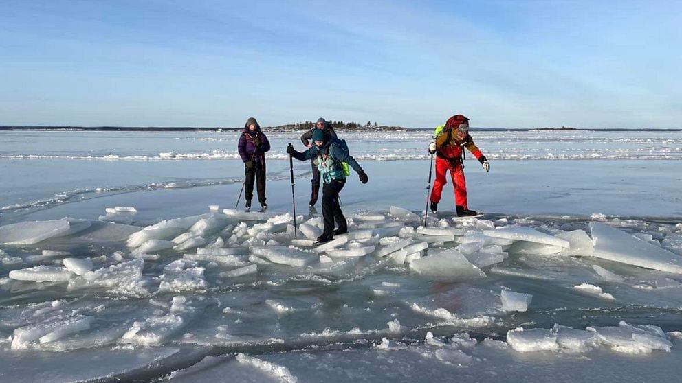 Fyra långfärdsskridskoåkare på havet som klättrar över en ränna med isflak som tornade upp