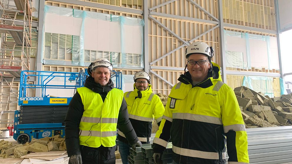 Tre män, Andreas de Jounge, fastighetschef på Uppsala Akademiförvaltning, Niclas Ahlm, projektchef och Jan Person, produktionschef på entreprenaden, i gula västar står framför en stor vägg med reglar.
