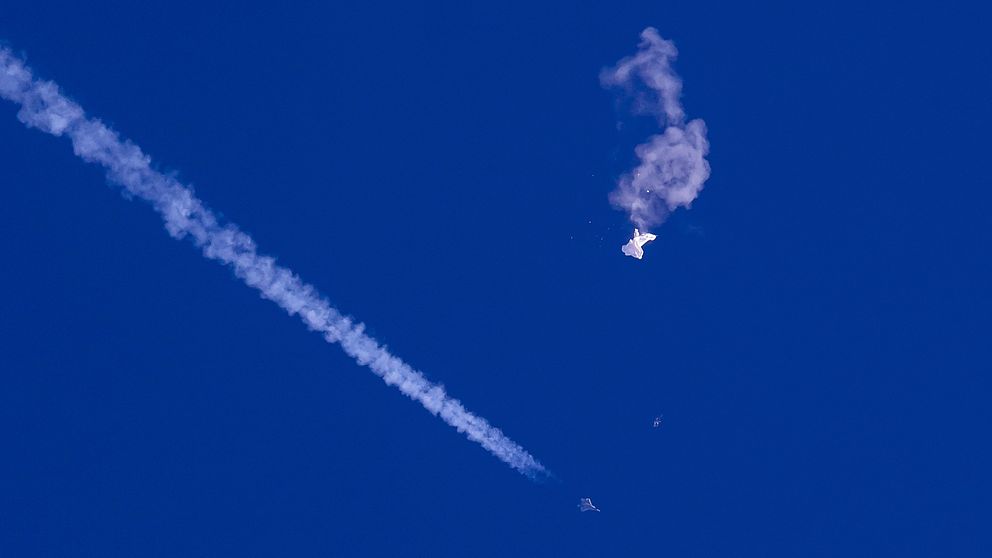 En vit ballong mot en blå himmel singlar punkterad ner mot marken.