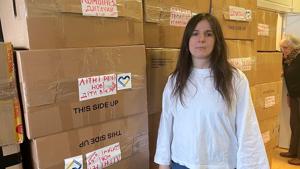 Läkaren Katja Blagodyr står bredvid lådor med barnkläder och leksaker som ska till barnhem i Ukraina