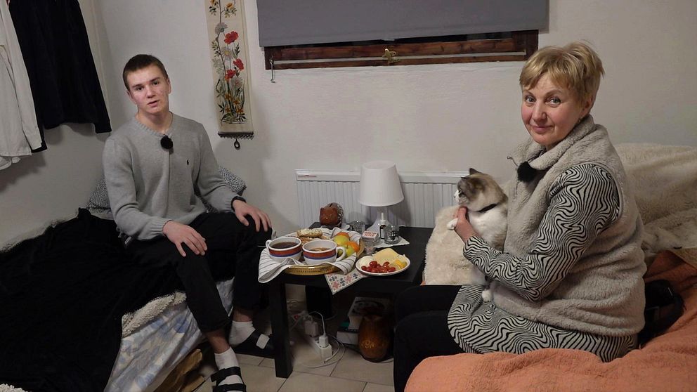 Ukrainska Tymofii Gorpynych och hans mamma Nataliya sitter i sin lilla lägenhet utanför Vellinge. Bordet är dukat med fika och mamman har en katt i famnen.