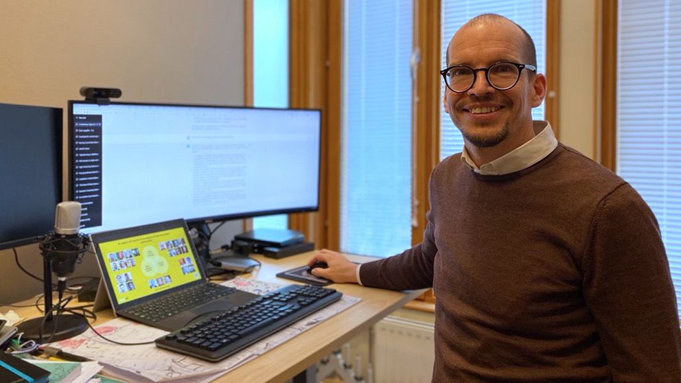 Lektorn Jörg Pareigis på Karlstads universitet står vid datorskärmar och ler in i kameran.