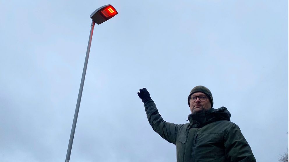 Andréas Hall, utvecklingsingenjör på stadsbyggnadsförvaltningen i Helsingborg, står i Pålsjöskog och pekar på en gatulampa som lyser rött.