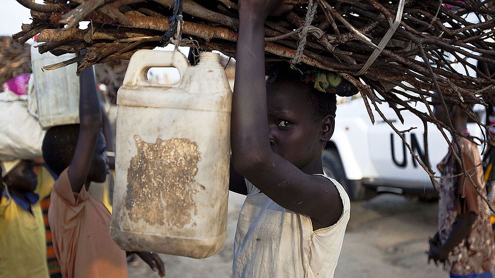 En ung kvinna bär brasved utanför FN-lägret i Bentiu, Sydsudan.