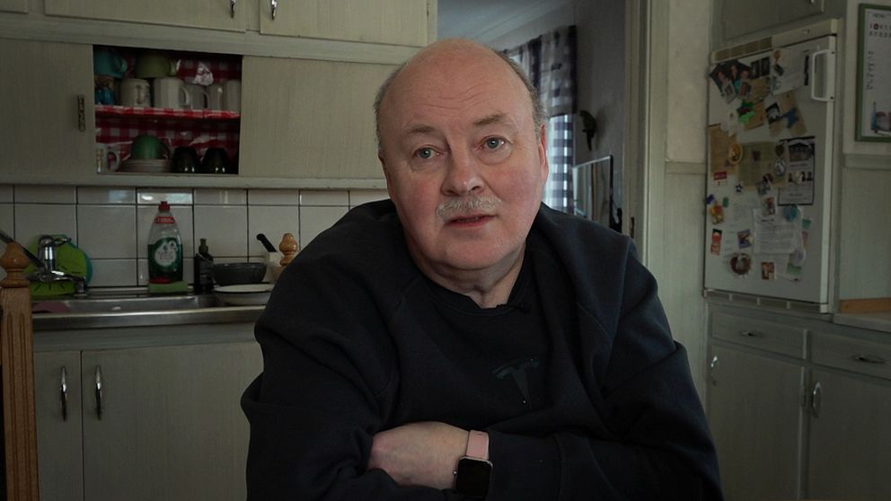 Mikael Ivarsson, en man med mustasch sitter i sitt kök i Tandsbyn med korslagda armar