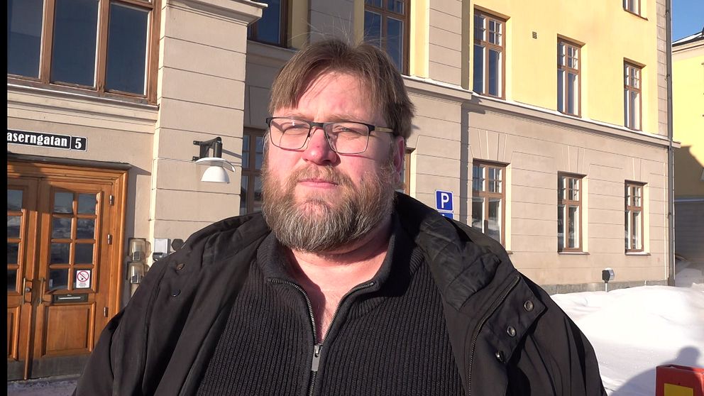 Andreas Lundgren intervjuas framför stadshuset i Umeå. Har svart jacka och svarta glasögon. Brunt hår och brunt skägg.