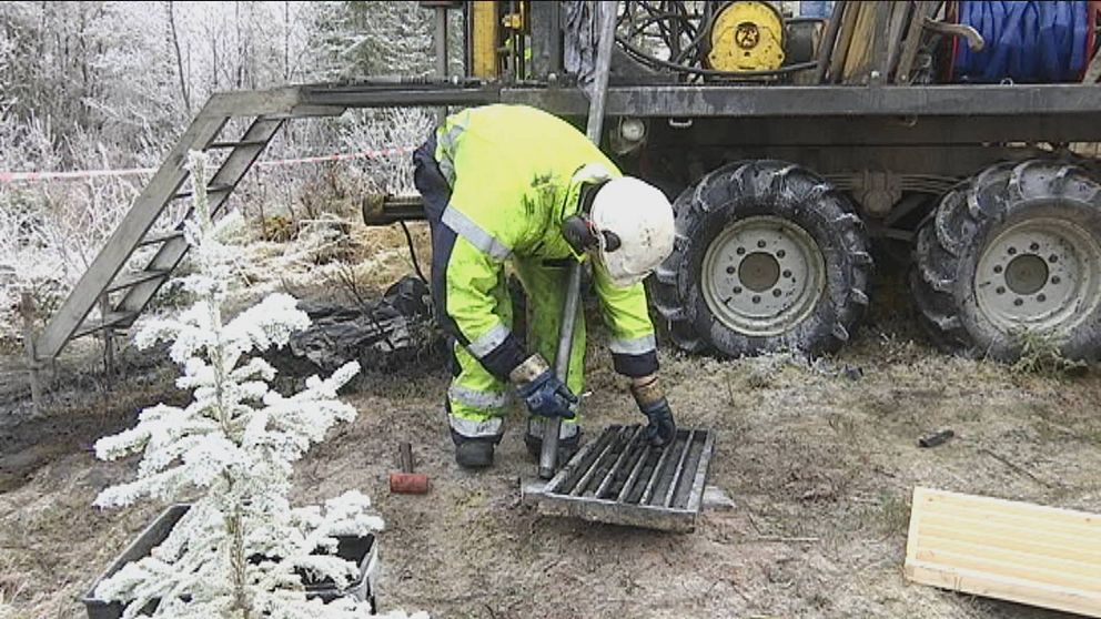 Bild på person i gula varsekläder vid en borrigg. Mannen är böjd över en låda med borrkärnor.