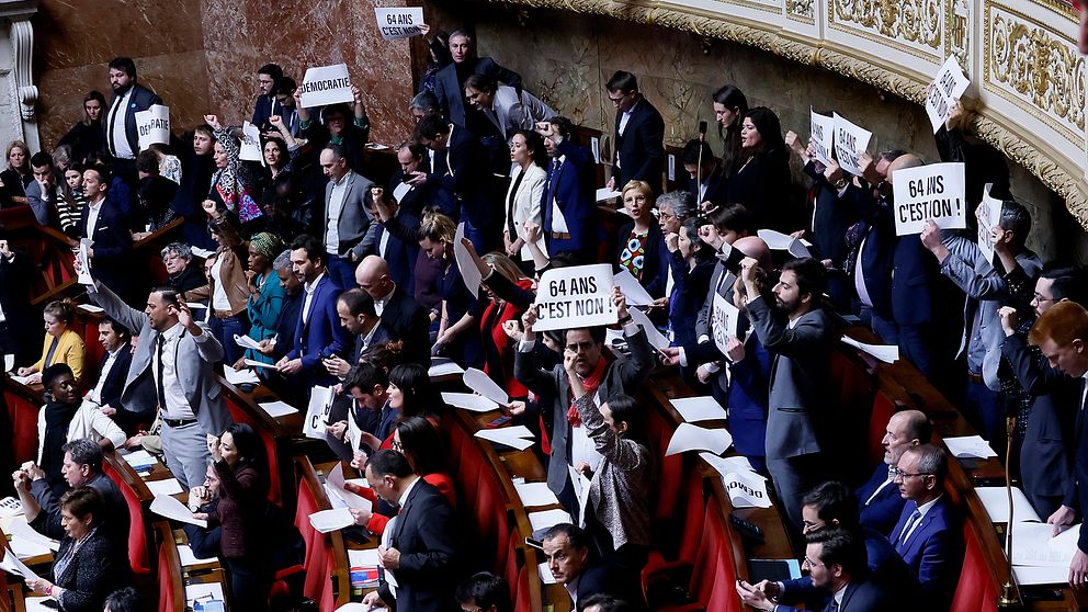 Franska parlamentet håller i plakat och sjunger.