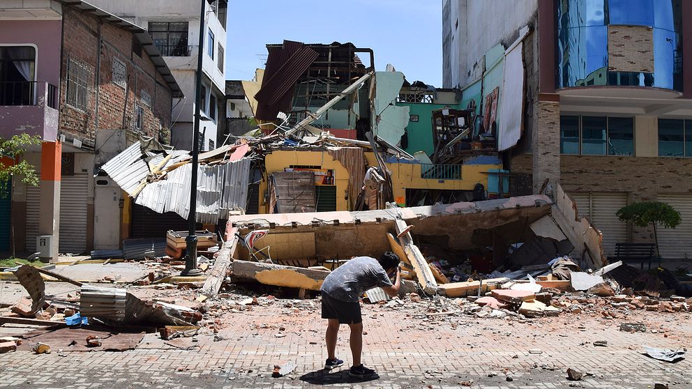 En man tar ett foto av en byggnad som kollapsade efter den jordbävning som skakade bland annat provinshuvudstaden Machala i Ecuador på lördagen.