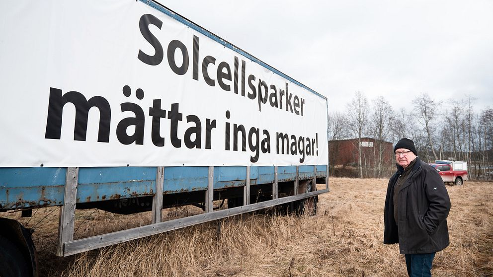 Lars-Gunnar Sandin står på åkermark vid sin stora uppsatta skylt där det står ”Solcellsparker mättar inga magar”. Nu ska skylten ner.