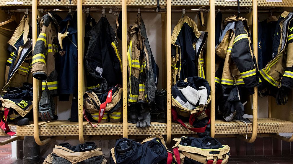 Bild från ett omklädningsrum med brandmännens arbetskläder upphängda.