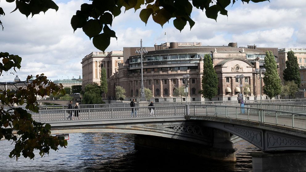 Riksdagshuset i septembersolen. Några löv syns i förgrunden.