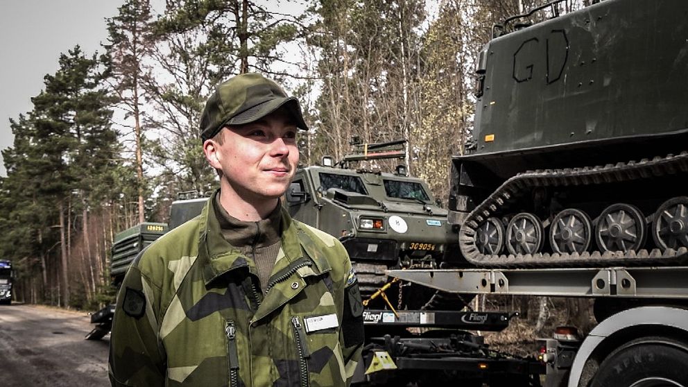 Värnpliktige Gustavsson som är en de vid Dalregementet som nu ansluter till övningen Aurora-23. Han står vid en lastbil som lastad med en bandvagn och är på väg söderut där de ska agera en fiendebataljon tillsammans med delar från Livgardet och I21.