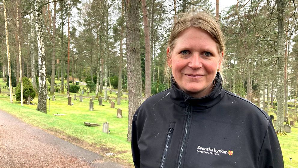 Elna Forsberg är kyrkogårdschef på i Karlstads pastorat står i halvkroppsbild på en kyrkogård. Hon ler mot kameran.