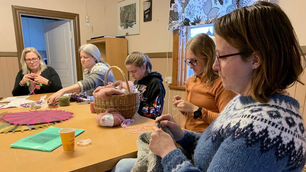 Fem kvinnor runt ett bord som handarbetar på en syjunta i Orsa