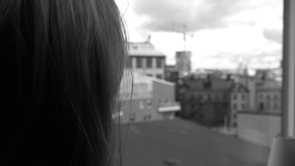 En kvinna tittar ut över takåsar i en stad