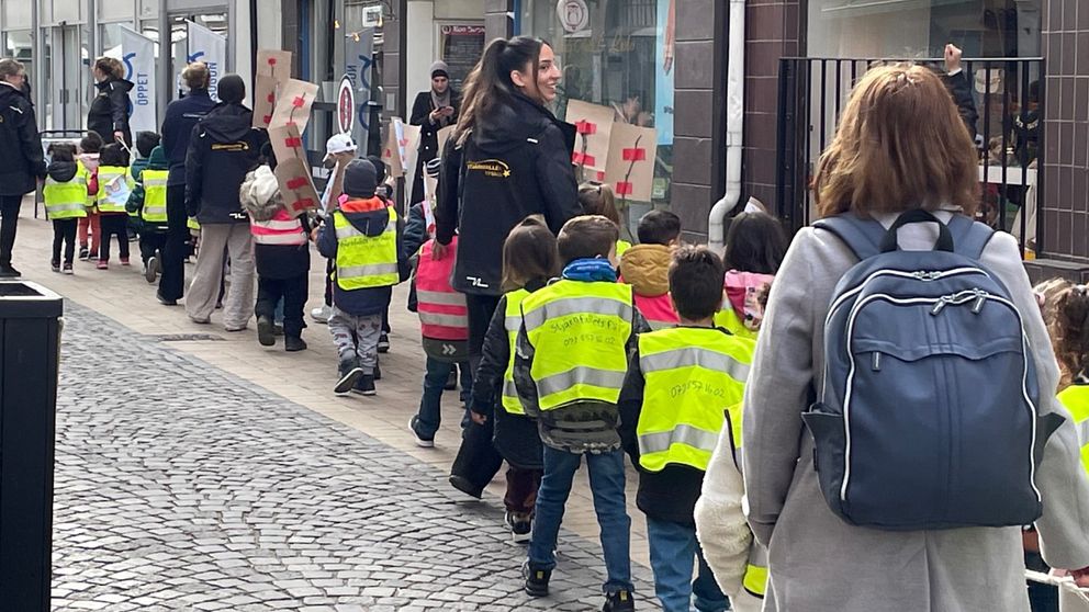 Barn och vuxna från förskola som går i ett demonstrationståg.