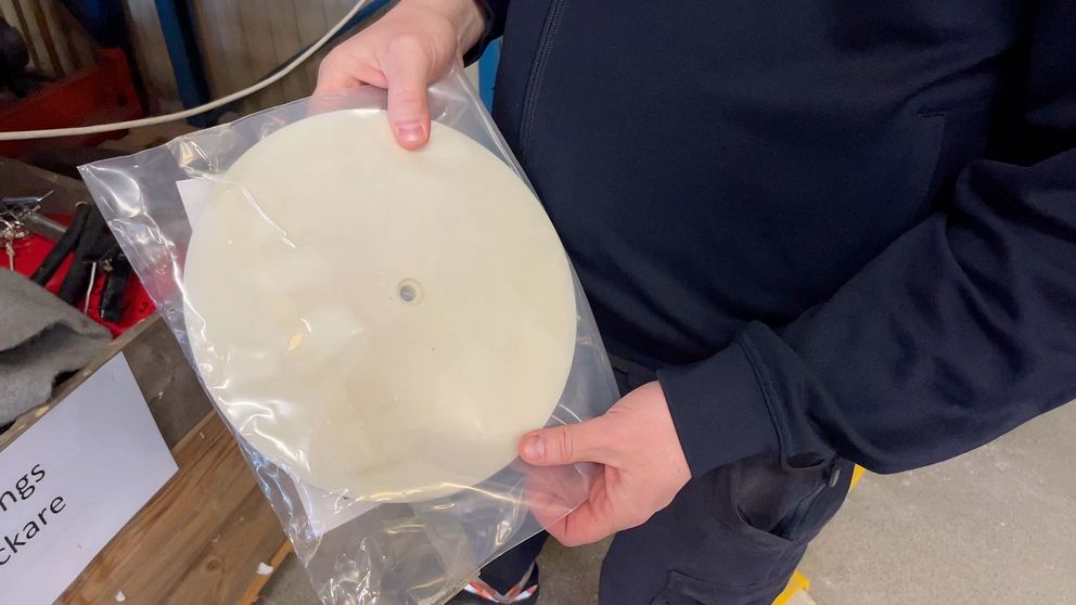 en person håller i ett beigt, runt plastlock.