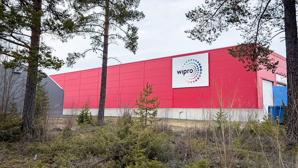 Ceriserosa stor plåtbyggnad med en vit skylt som det står ”Wipro” på.