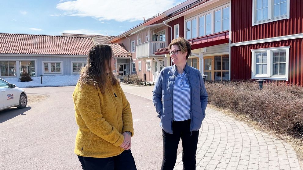 Två kvinnor på bild framför ett trähus i olika färger. Kvinnan till vänster har en gul fleecetröja, Jessica Holmström, och den andra kvinnan har en blå dunjacka, Monica Salmonsson.