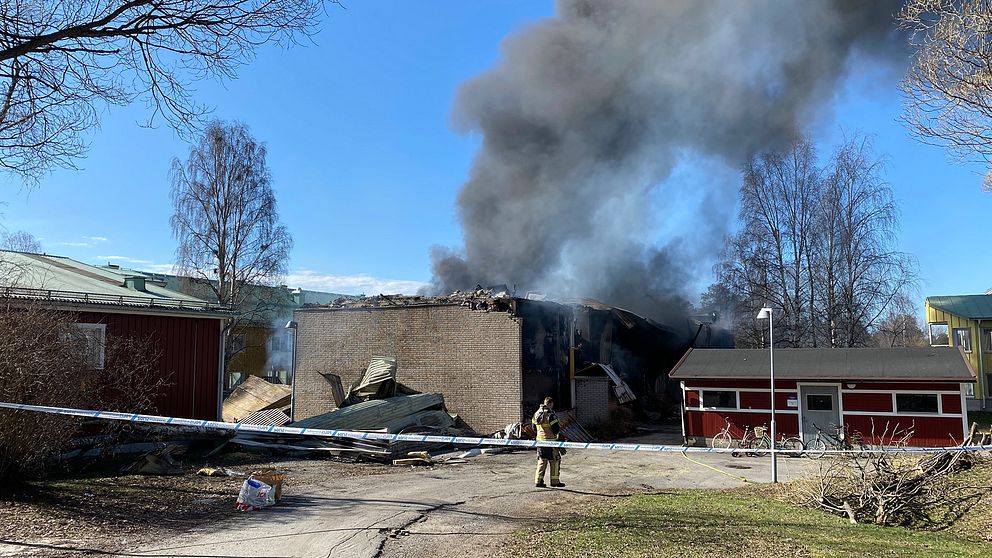 rykande byggnad med tegelgrunden kvar, brandman, polisavspärrning