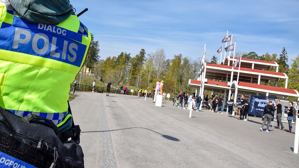 Närbild på polisväst där det står ”dialog polis” till vänster, Furuviksparken syns till höger, människor utanför.