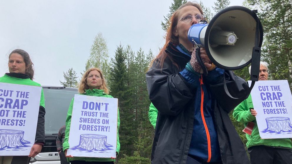 Elin Lundqvist Burlin med en megafon, i bakgrunden tre demonstranter med plakat