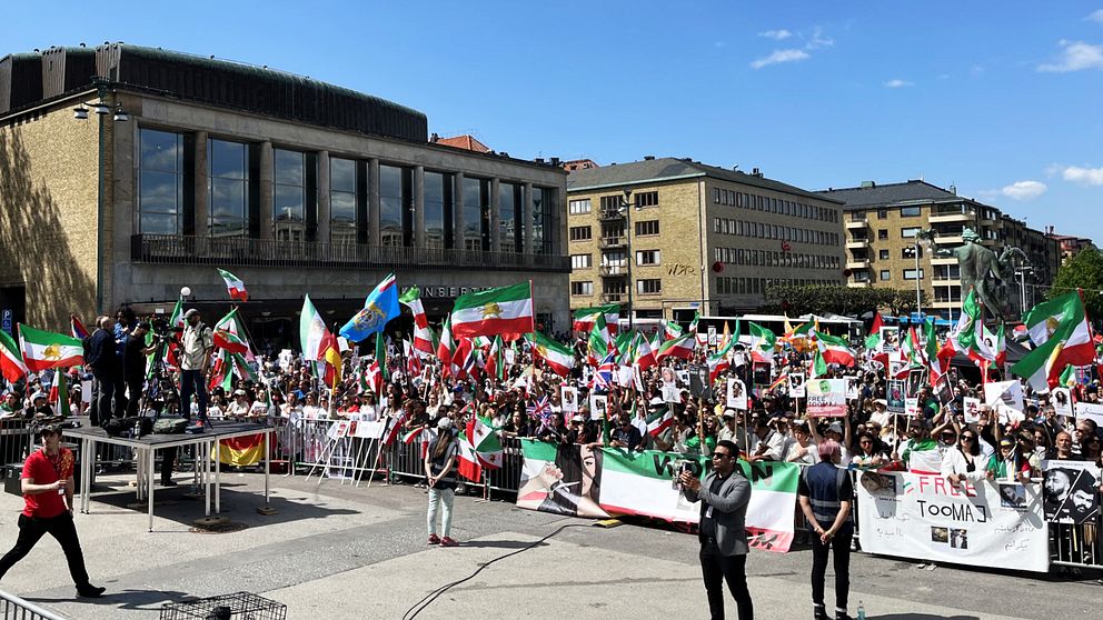 Götaplatsen i Göteborg en solig majdag. På bilden syns flera männsikor som demonstrerar mot den iranska regimen.