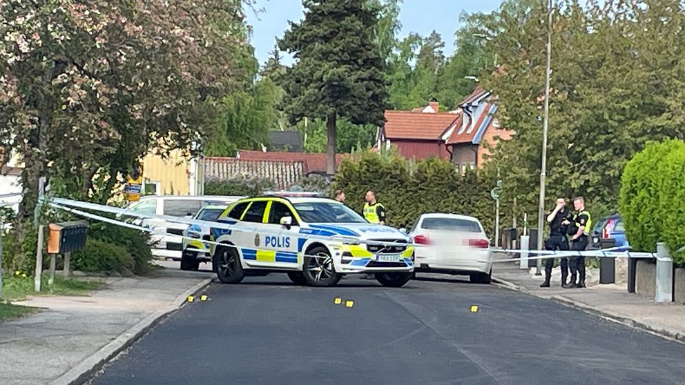 Polisbilar på bostadsgata med flera utmarkerade nummer för teknisk undersökning.