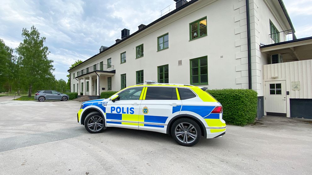 Polisbil står parkerad utanför en vit, äldre byggnad, där det drivs ett sis-hem.