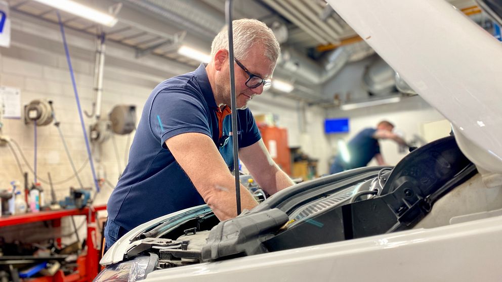 Verkstadsägaren Richard Åndberg står och tittar ned i motorn på en bil.