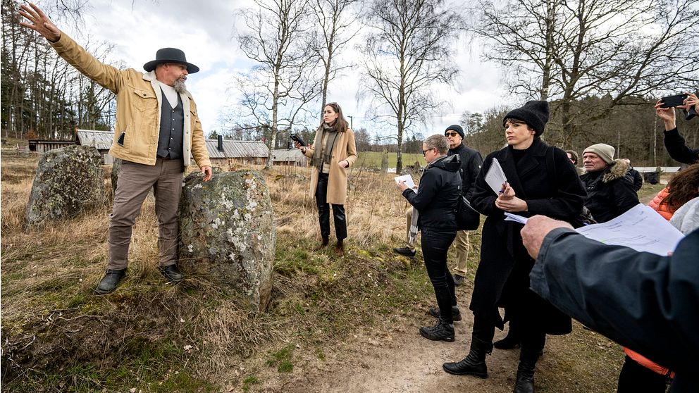 Vikingabyns ägare Oddvar Lönnerkrantz vid en av stenarna på Vätteryds gravfält. Han gestikulerar och förklarar för tingsrättens ledamöter som har syn på plats. Bilden är tagen under rättegången i Hässleholms tingsrätt.