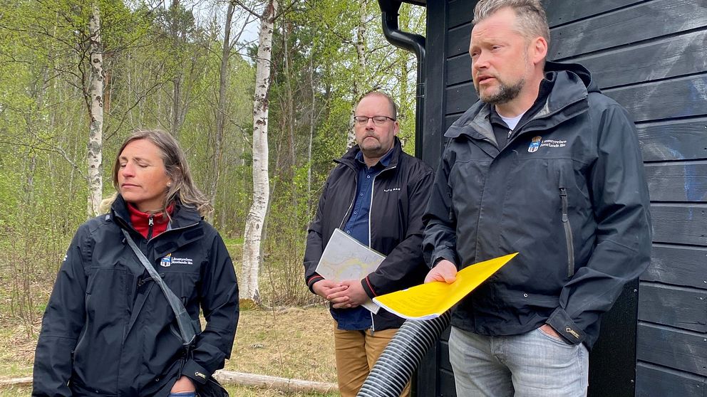 Anna Löfholm vattenhandläggare länsstyrelsen, Joakim Svensson, länsfiskekonsulent och Jens Fuchs, chef på Vattenenheten länsstyrelsen står utomhus med papper och kartor i händerna.