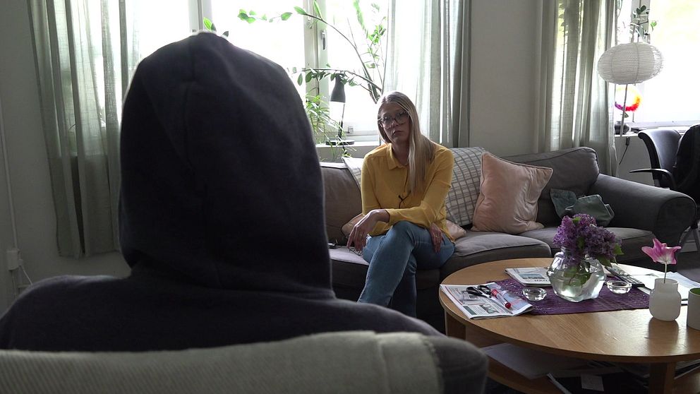 Bild på en person som är anonymiserad, man ser bakhuvudet på personen. Framför personen sitter SVT:s reporter Fanny Asplund i en soffa.