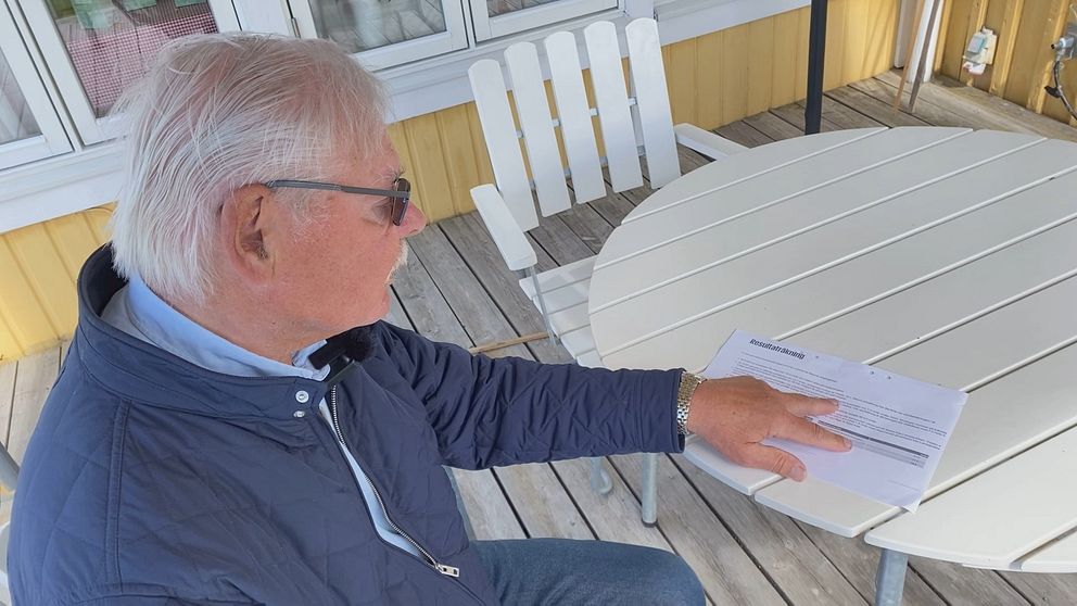 Revisorn sitter utomhus och pekar med handen på ett papper. ”resultaträkning” står det längst upp på pappret. Han har solglasögon och en mörkblå jacka på sig.