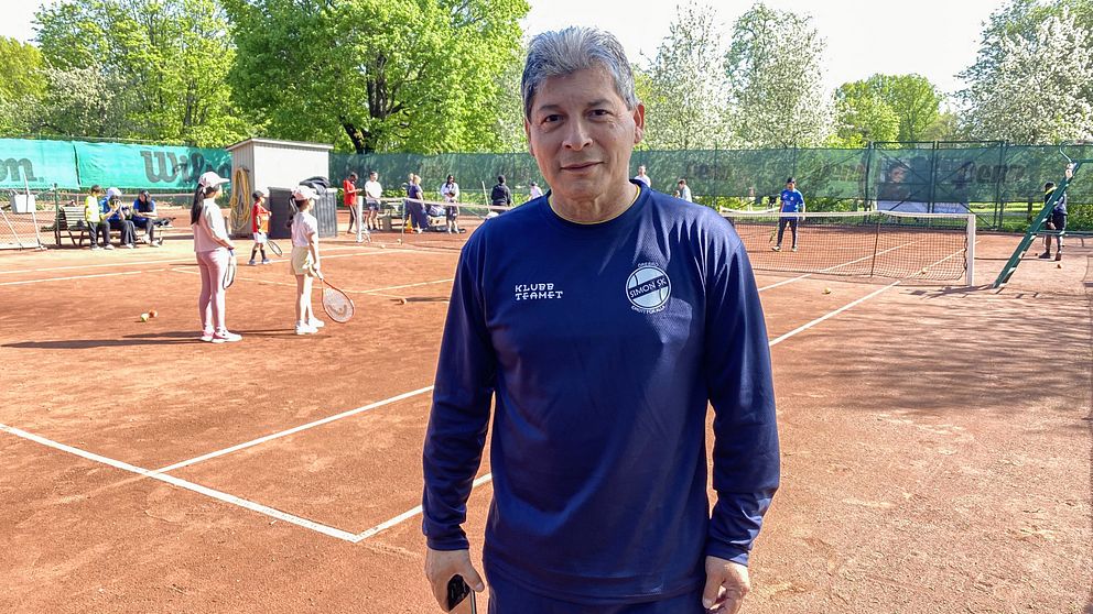 En man, Martin Mestanza projektledare för Tennis på gatan, står på en tennisbana och tittar in i kameran.