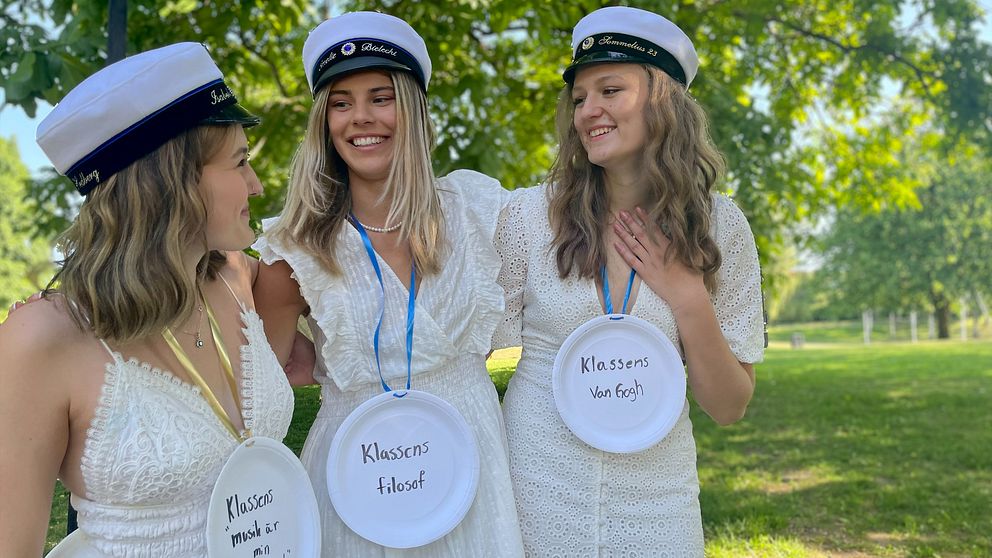 Tre kvinnliga studenter i en grönskande park.