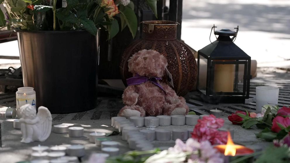 Blommor, ljus och en nalle vid minnesplatsen i Farsta där en 15-åring sköts ihjäl och tre personer skadades.
