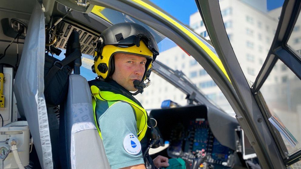 Tore Schultzberg, helikopterpilot, sitter i en helikopter. I bakgrunden Södersjukhuset.