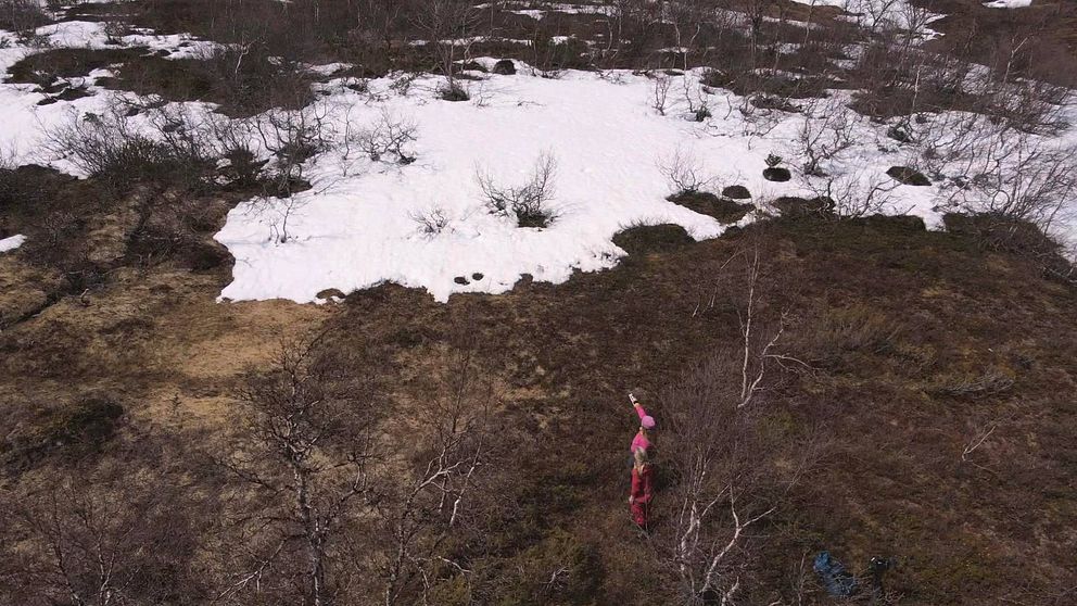 två personer som står på fjället, en av dem pekar upp mot en fjälltopp.