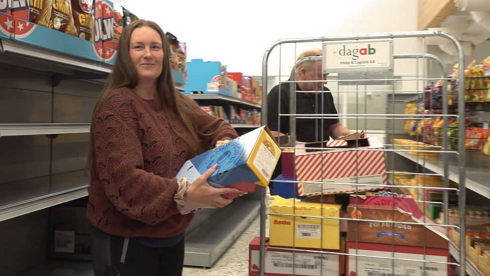 Pauline och Jörgen drar en vagn med varor förbi en hylla med chipspåsar i den obemannade butiken i Lögdeå.