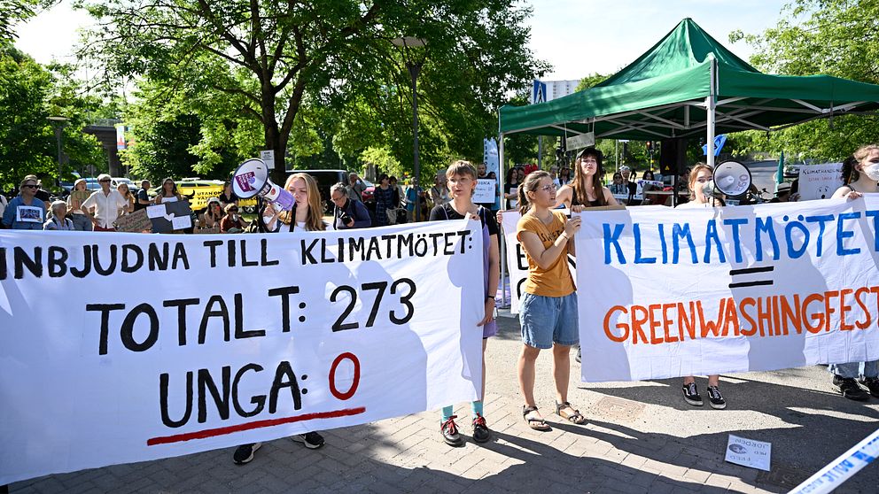Demonstranter med banderoller utanför hotellet där regeringen arrangerar klimatmöte