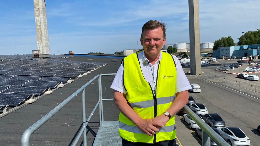 Man står framför solceller på ett tak.
