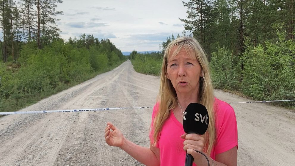 SVT:s reporter Marie Selander framför en polisavspärrning på en skogsbilväg i närheten av Vemhån.