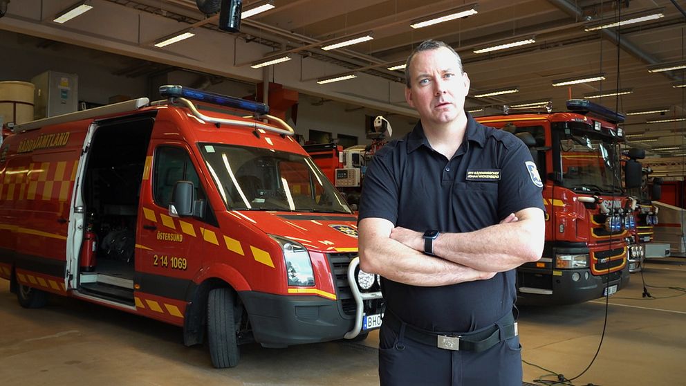 Johan Wickenberg, räddningschef, står med armarna i kors framför några brandbilar på brandstationen i Östersund.